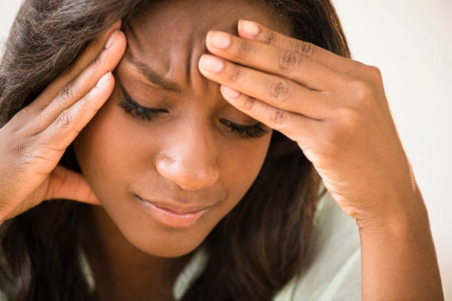 Black woman frowning with head in hands