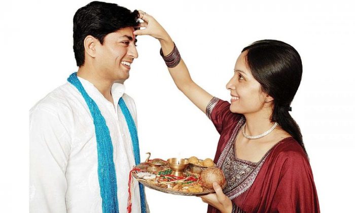 woman apply tilak on men